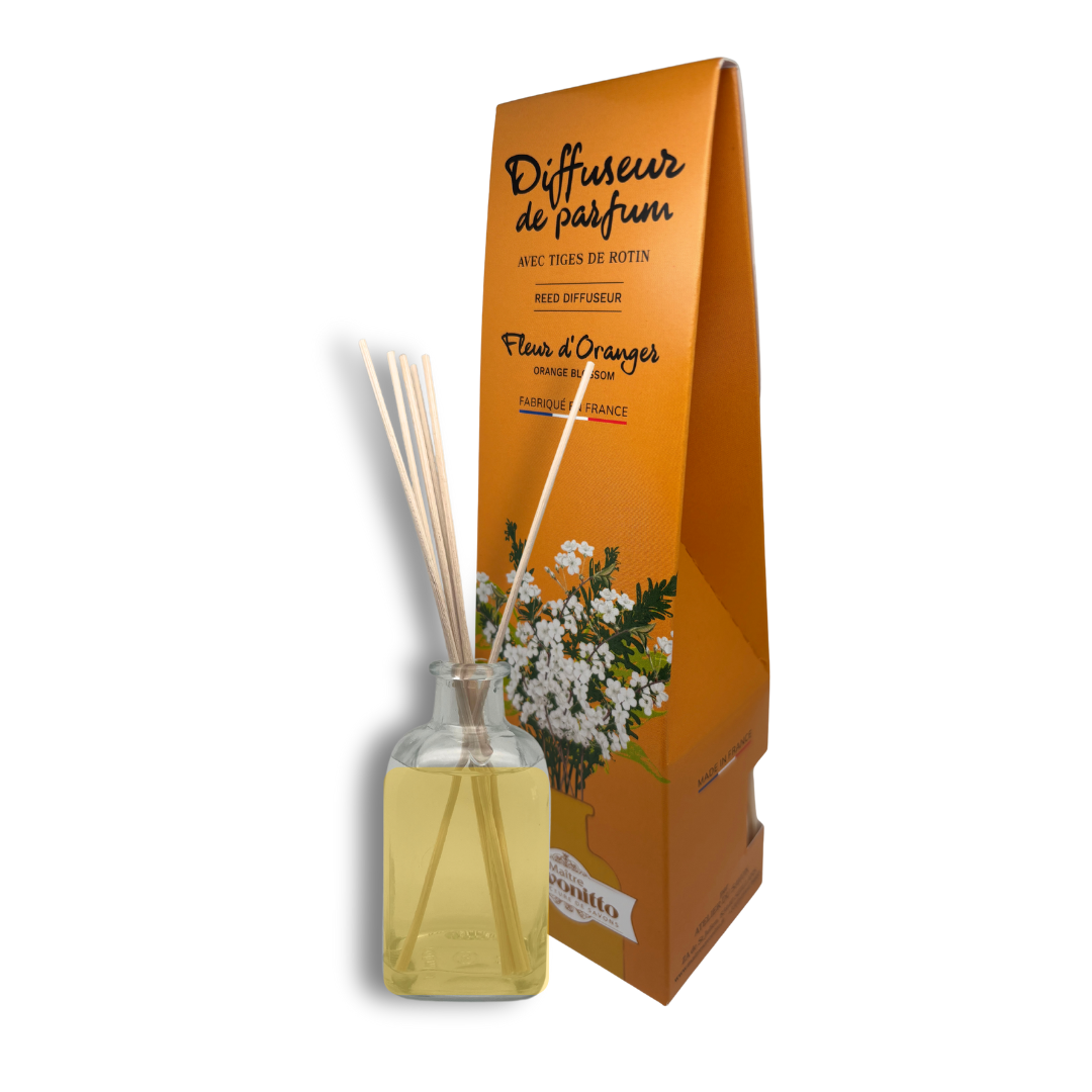 Diffuseur de parfum à la fleur d'oranger, fragrance solaire et apaisante présentée dans son flacon en verre avec ses tiges de rotin.