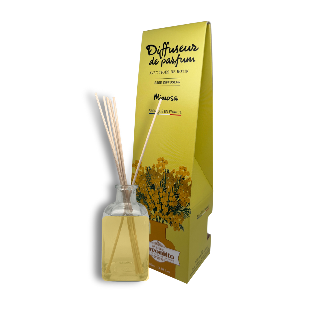 Diffuseur de parfum au mimosa, fragrance poudrée et printanière présentée dans son flacon en verre avec ses tiges de rotin