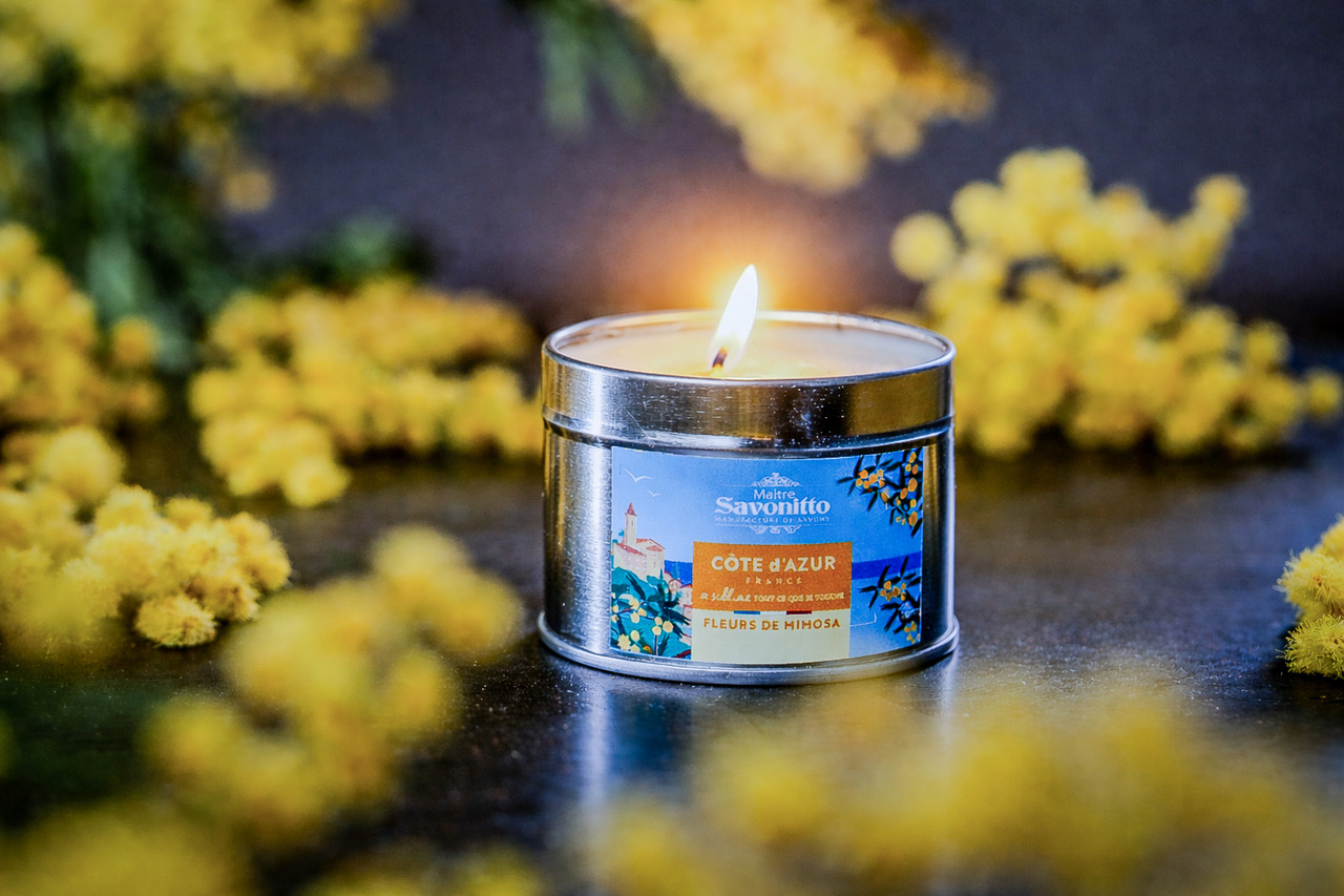 Bougie parfumée Mimosa – Côte d’Azur Bougie parfumée au mimosa dans une boîte métal, entourée de fleurs jaunes, ambiance chaleureuse