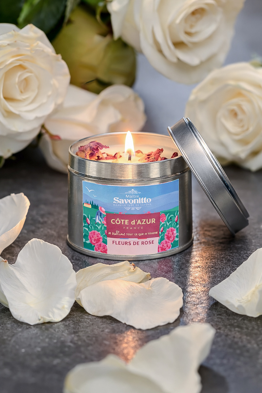 Bougie parfumée Rose – Côte d’Azur Bougie parfumée à la rose dans une boîte métal, entourée de pétales de rose blanche, ambiance élégante